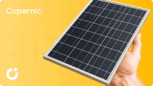 ręka trzymająca panel fotowoltaiczny, żółte tło z logiem firmy copernic